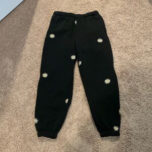 These are black baggy sweatpants with daisies from SHEIN.